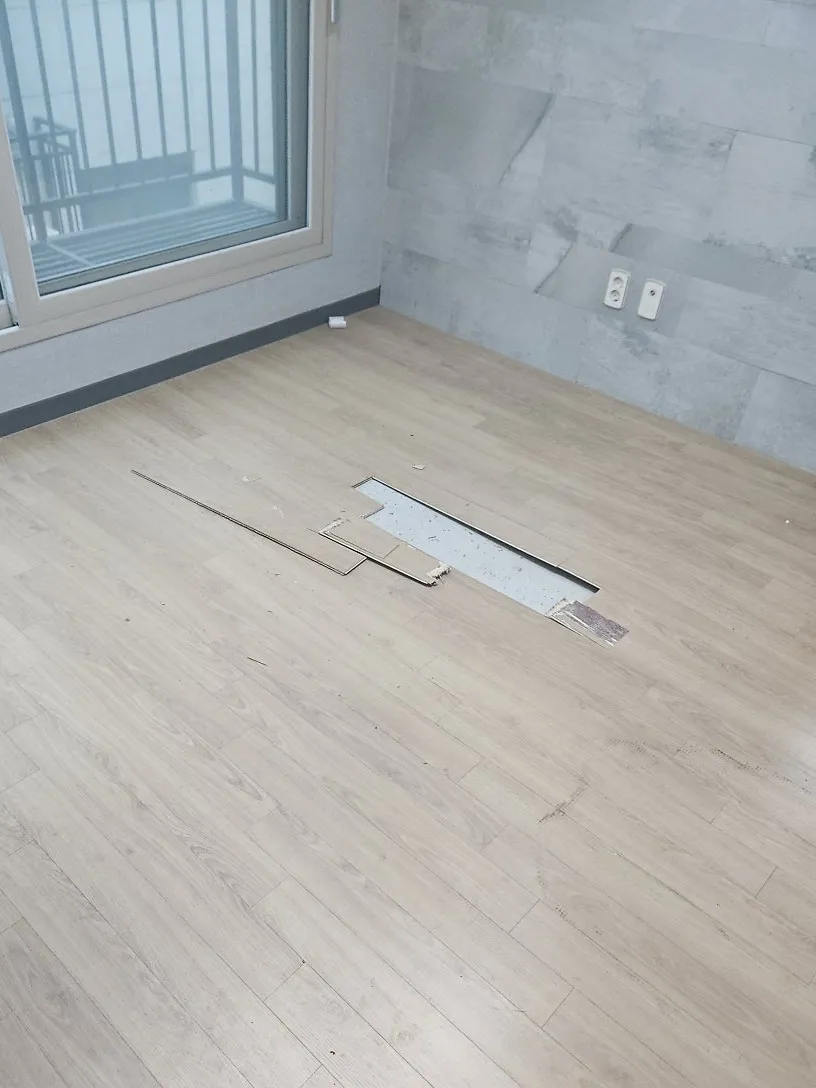 창가 쪽 바닥 마루 일부가 들떠 벌어진 방