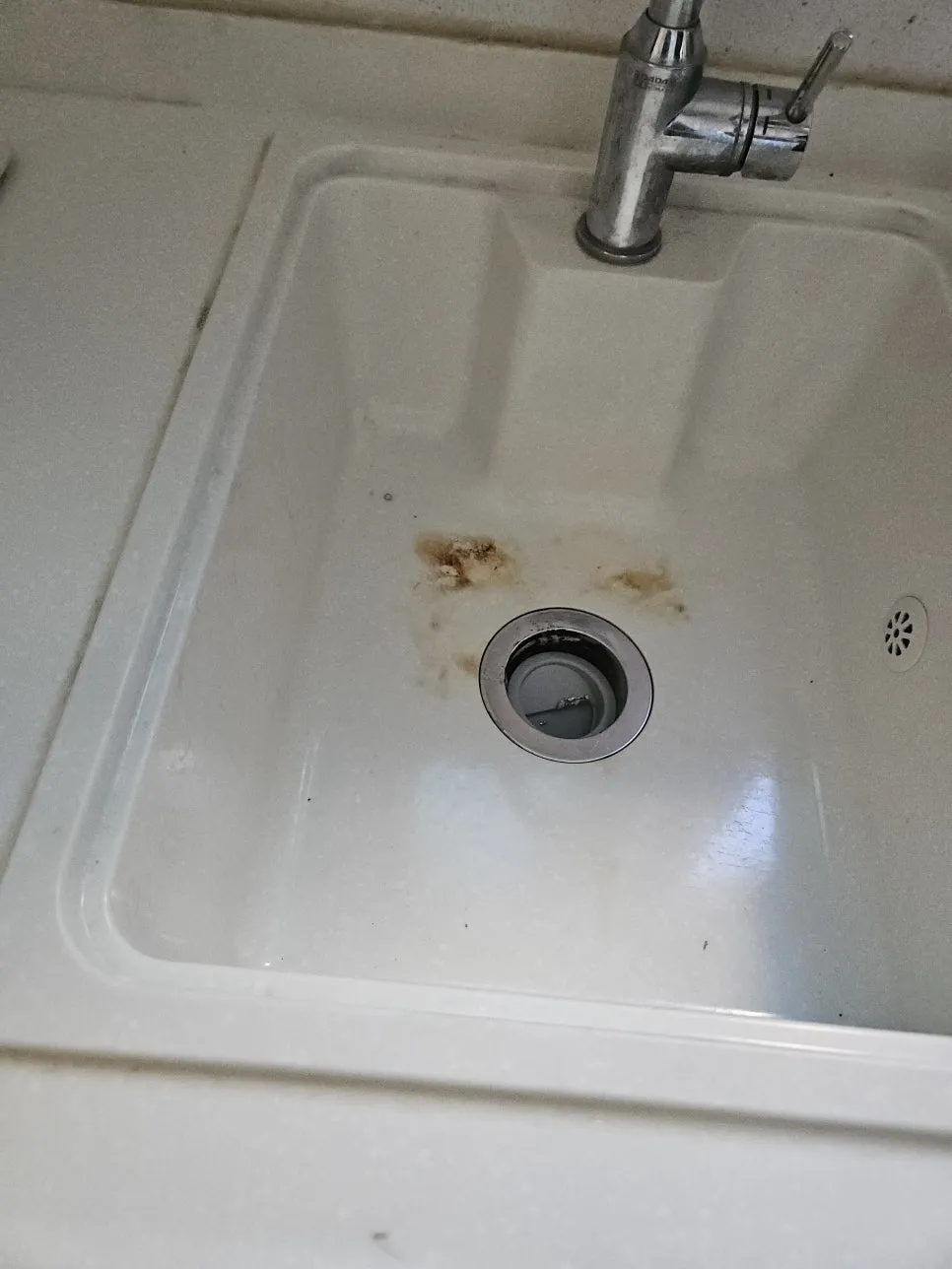 배수구 주변에 갈색 탄 자국이 남은 흰색 인조대리석 싱크볼